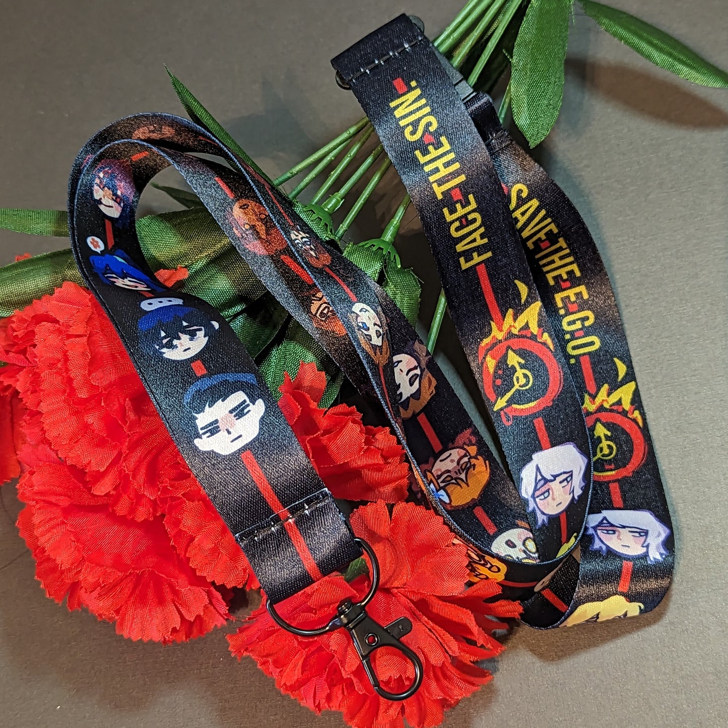 A breakaway lanyard with a chibi head of all the sinner and the text "Face the sin. Save the EGO."